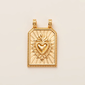 Close-up of golden vintage tarot heart pendant with sunburst texture and beaded edges
