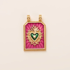 Detail of vintage tarot-style pendant with green heart and red enamel ray texture