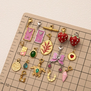 Macro shot of assorted gold-plated pendants including strawberry and turtle on a grid mat