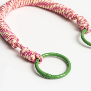 Detailed macro view of handmade pink and yellow woven rope keychain with green metal rings
