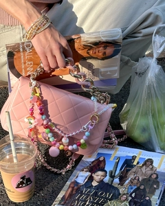 Detail der rosa gesteppten Ledertasche mit bunten Perlenanhängern und Goldkette