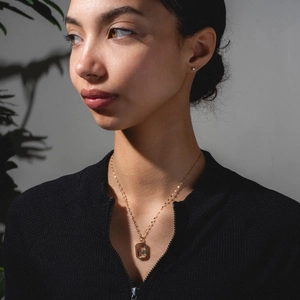 Modelo luciendo un collar relicario vintage de oro de 18k con colgante rectangular claro