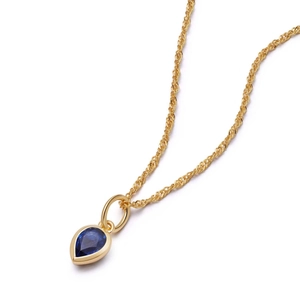 Detail eines birnenförmigen blauen Edelsteinanhängers an einer goldenen Kordelkette