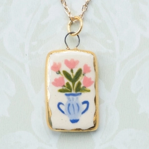 Dettaglio di un ciondolo rettangolare in oro 18K con inserto floreale in ceramica