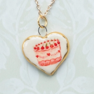 Dettaglio del ciondolo a forma di cuore con catena in oro 18 carati e motivo torta