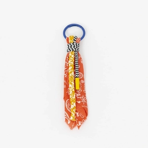 Detail of colorful paisley fabric and yellow braided cord on a creative keychain charm