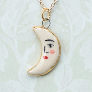 Dettaglio del ciondolo a luna dipinto a mano con viso e catena in oro 18K coordinata
