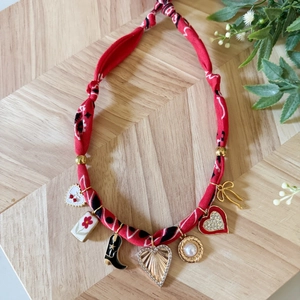 Collana in tessuto floreale con ciondoli a cuore e stivale su legno naturale