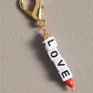 Détail du pendentif LOVE en perles avec goutte rouge et fermoir mousqueton doré