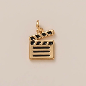 Detailed view of movie clapperboard charm pendant in gold finish with black enamel
