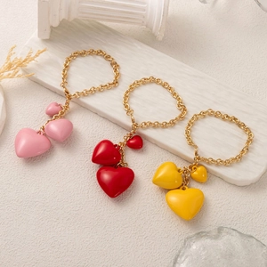 Three colorful resin heart pendants with gold chains in pink, red, and yellow colors