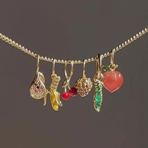 Detail van de gouden ketting met kleurrijke emaille fruitbedels en kristallen