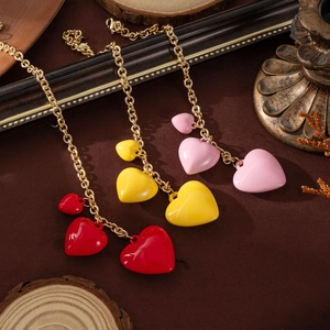 Detail of red, yellow, and pink heart charms on gold chains with a retro wooden background