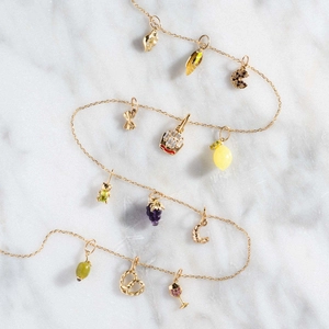 Detailweergave van gouden ketting met fruitbedeltjes van citroen en druiven van hars