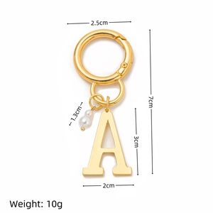 Detailed view of golden letter A keychain with a small pearl accent on white background