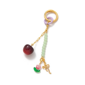 Cute fruit-themed keychain with red cherry, green beads and golden bow on white background