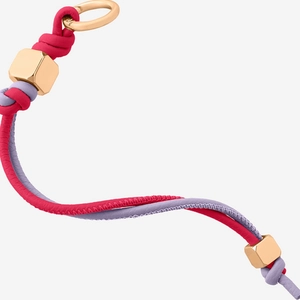 Macro view of woven strawberry pendant keychain with rose red cords and gold metal rings