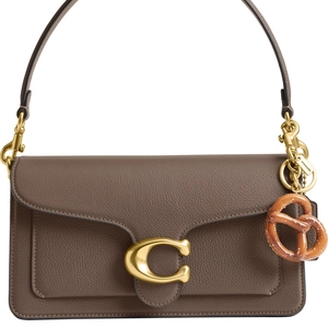 Detail view of leather bag featuring a gold C-buckle and stylish pretzel keychain