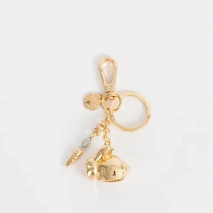Détail d'un porte-clés lapin doré avec pendentif carotte et plaque métallique gravée