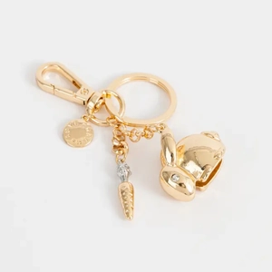 Détail du porte-clés lapin et carotte dorés avec pendentif rond gravé et fermoir mousqueton