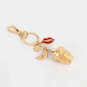 Vue détaillée du porte-clés doré avec pendentifs tasse à café croissant et lèvres rouges