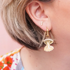 Detail of 18K gold plated farfalle pasta pendant earring with white zircon stud on model