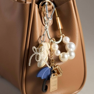 Kleurrijke mode tassenhangers met mini-laarzen en blauwe paraplu op leren tas