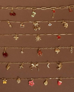 Détails à plat de pendentifs plaqués or 18 carats avec breloques cerise et cœur sur fond texturé