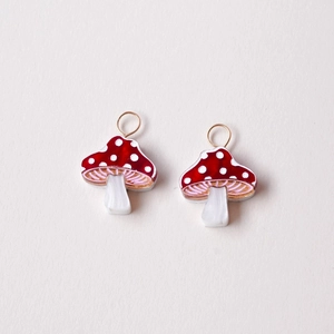 Detail of red mushroom charms with white dots and gold rings for DIY jewelry making