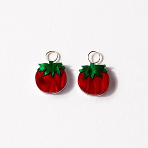 Detail of 18K gold-plated tomato pendant with translucent red texture and green leaves