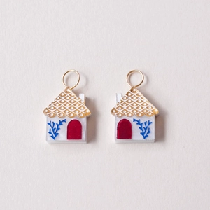 Detail of 18K gold-plated house-shaped pendants with white resin and red door design