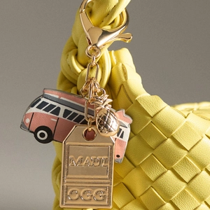 Macro-opname van Maui OGG gouden hanger met ananas en kleurrijke bus sleutelhanger detail