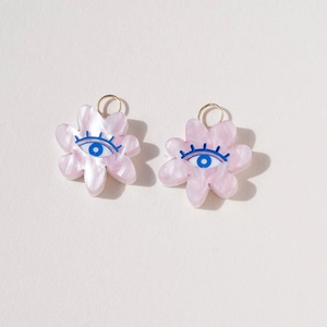 Close-up of pink flower pendants with evil eye pattern and 18K gold-plated rings