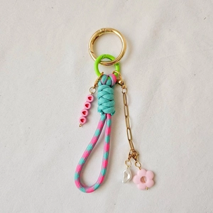Close-up of woven turquoise and pink rope keychain with heart beads and gold spring clasp