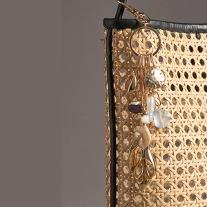 Détail d'un bijou de sac avec feuille d'or, coquillage et résine sur un sac en paille