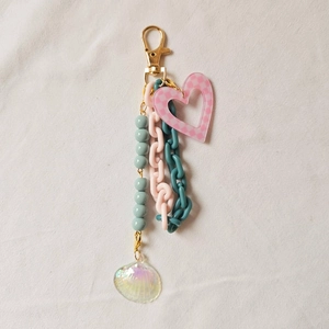 Detail of pink heart keychain with blue acrylic chains and a shimmering shell charm
