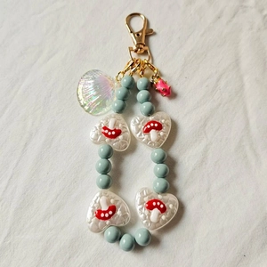 Detail of beaded keychain with blue beads, mushroom heart charm and shell pendant