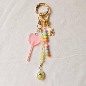 Detail of pink lollipop and cute bear charms on a golden DIY keychain accessory