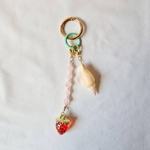 Detail of creative strawberry and seashell keychain with pink beads and golden rings