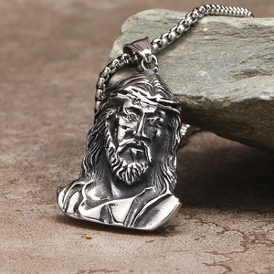 Detail shot of vintage silver Jesus head pendant with thorns on a natural rock background