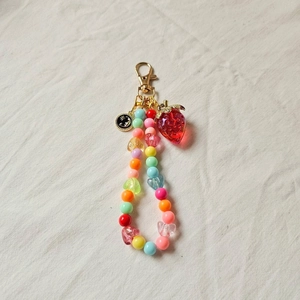 Detail of colorful acrylic beads and golden star-moon charms on a strawberry keychain