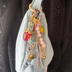 Detail showing a colorful mix of strawberry charms and silver bow pendant on a bag