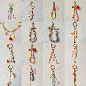 Variety set of 16 colorful handmade beaded keychains with charms on linen background