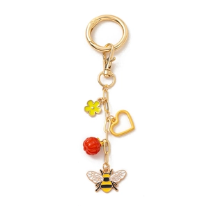 Détail d'un porte-clés doré avec un pendentif abeille et des breloques en émail