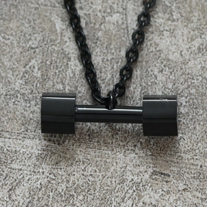 Macro shot of black dumbbell pendant necklace showing the polished metal texture