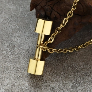 Detail of a golden dumbbell pendant on an O-chain over a rustic wooden block