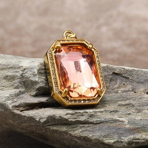 Detail of a rectangular champagne gemstone pendant with zircon halo on a natural stone