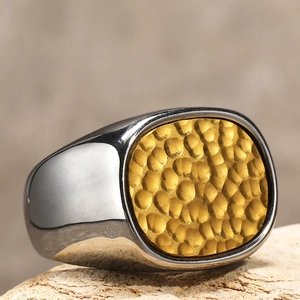 Nahaufnahme eines silbernen Titanstahlrings mit gehämmerter goldener Oberfläche.
