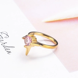 Elegante anello dorato con gemma rosa e montatura geometrica in stile minimalista