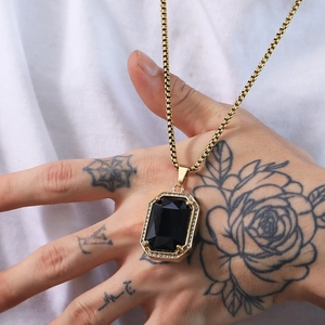 Detail of hip hop gold chain with a large square black gemstone pendant and zircon accents